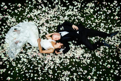 Bride and groom lay in a bed of flowers.