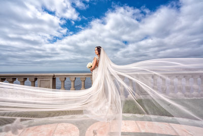 Bride posing at beach with beautiful veil