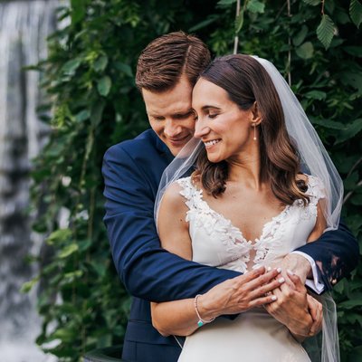 bride and groom snuggle beside ancaster mill waterfall