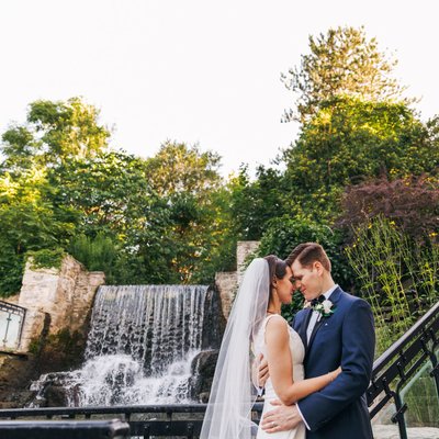 bride and groom on stairs to waterfall at ancaster mill
