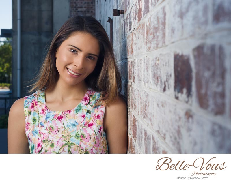 Model In Floral Dress Posing Next To Brick Wall