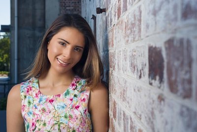 Model In Floral Dress Posing Next To Brick Wall