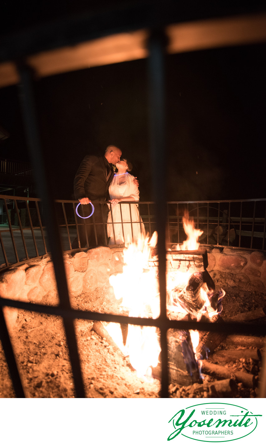 Bride And Groom Kiss Behind Fire Pit At Tenaya Lodge