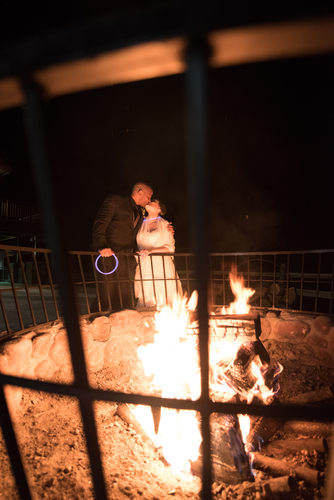 Bride And Groom Kiss Behind Fire Pit At Tenaya Lodge