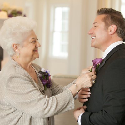 Mom pinning son's boutonnière on his wedding day