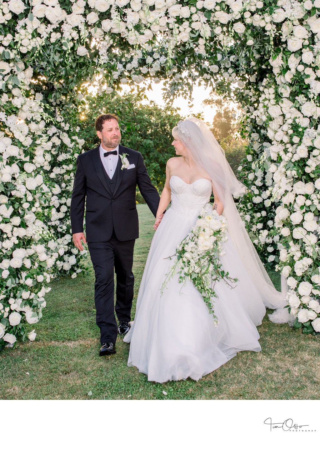 bride and groom under flower arch