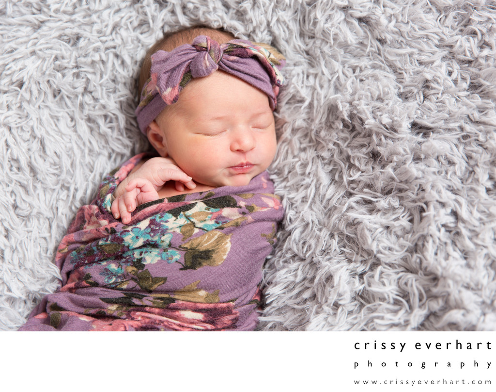 Sleeping baby girl in purple flowered swaddle