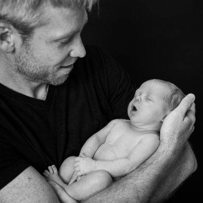Father Holding Newborn Sleeping Son in Arms