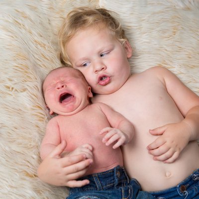 Two Year Old Holds Crying Newborn Brother