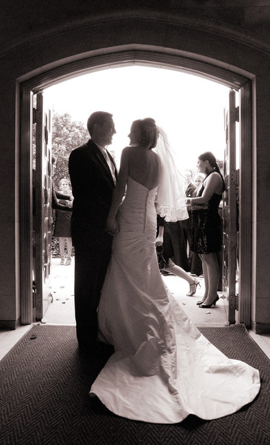 Bride & Groom silhouetted in doorway, Guests await exit