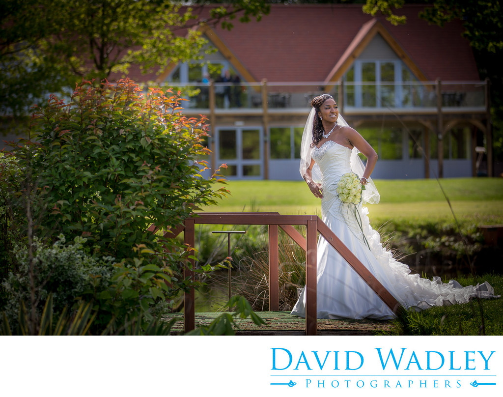 Bride on bridge with clubhouse at Nailcote Hall.