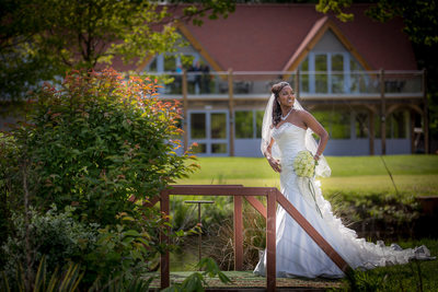 Bride on bridge with clubhouse at Nailcote Hall.