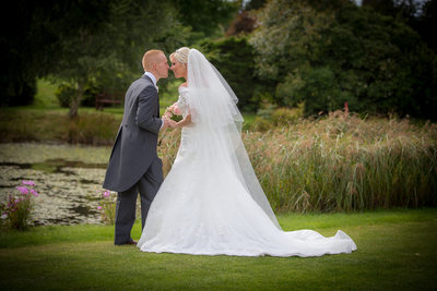 Kissing the bride in the lovely gardens of Nailcote Hall.