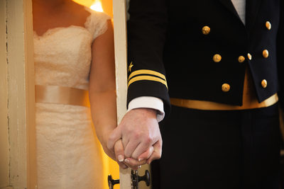 Bride and Groom hold hands around door 
