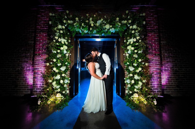 Bride and Groom Under Floral Archway at Press Room