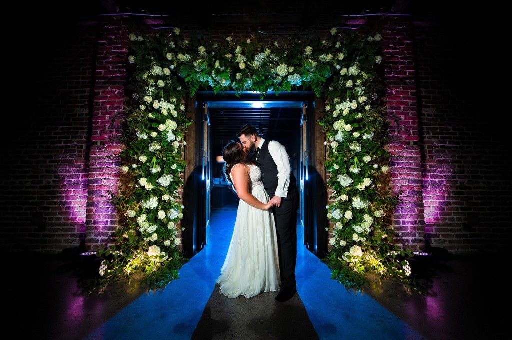 Bride and Groom Under Floral Archway at Press Room