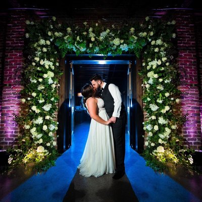 Bride and Groom Under Floral Archway at Press Room