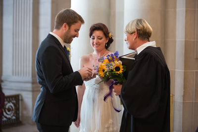 Groom puts ring on bride's hand during Rotunda ceremony