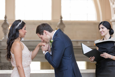 Groom kisses bride's hand during ceremony