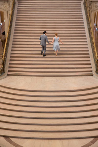 Bride groom ascend San Francisco City Hall staircase