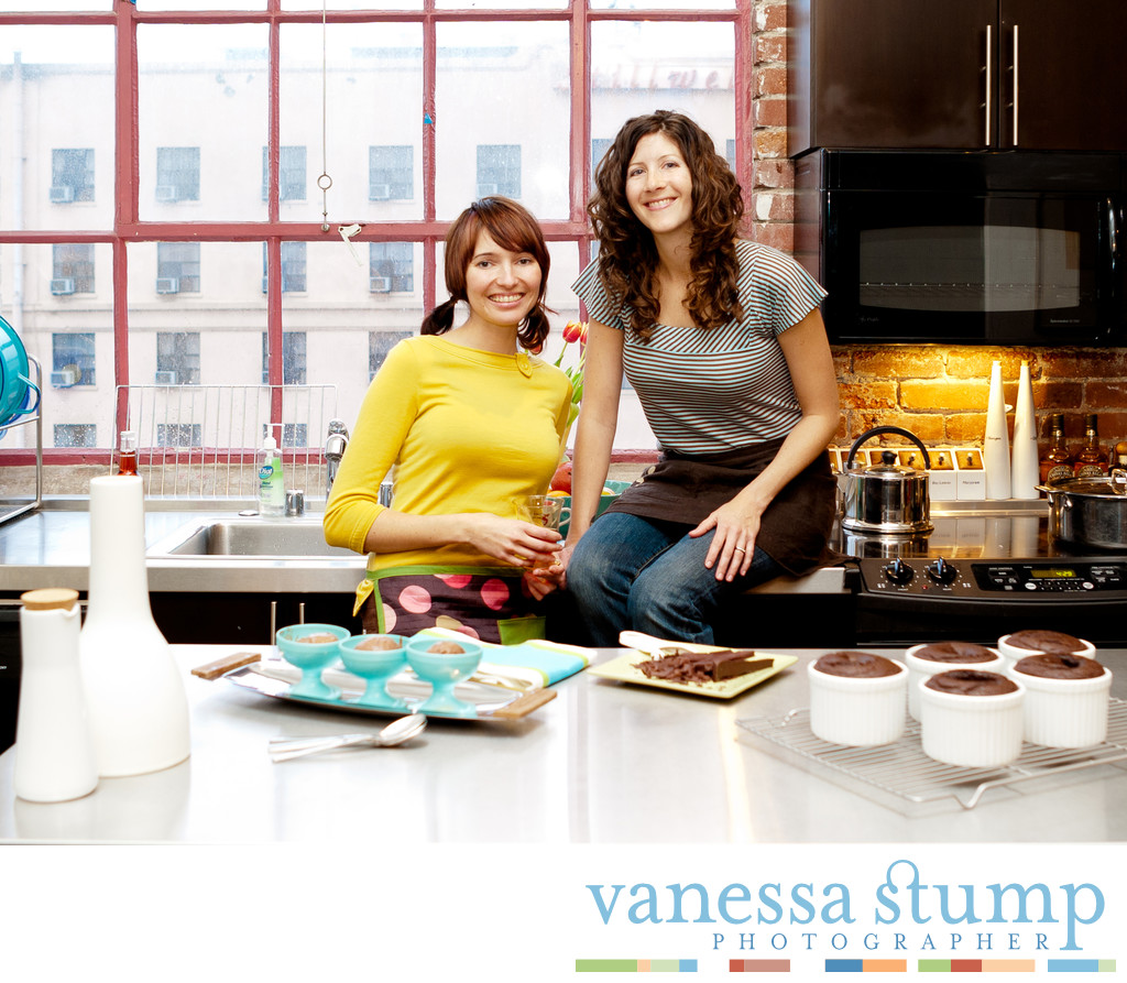Portrait of two smiling ladies in a kitchen with baked goods.