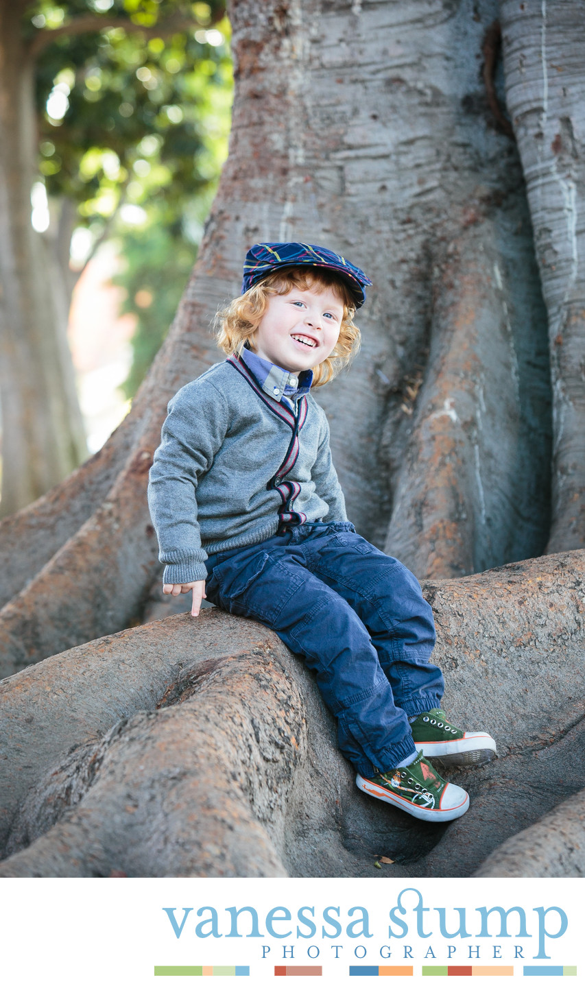 Portrait of cute young boy in newsboy cap sitting on a tree