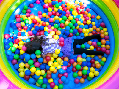 Little girl lying facedown in colorful balls at children's birthday party