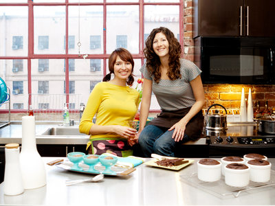 Portrait of two smiling ladies in a kitchen with baked goods.