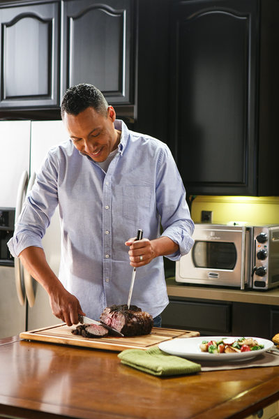Man in kitchen cutting a beef roast