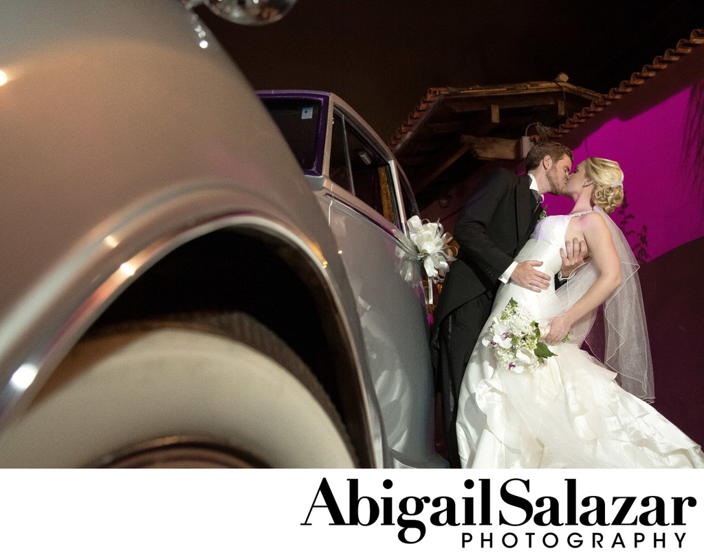 Bride & Groom kiss by classic wedding car