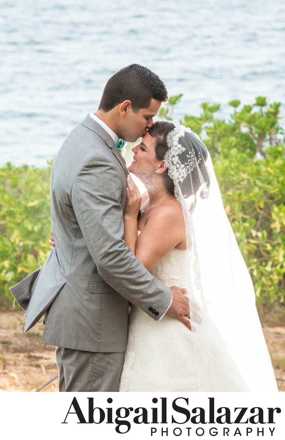Beach destination wedding: Groom kisses the bride