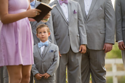 Cute Ring Bearer Holds His Hands Listening To Reader