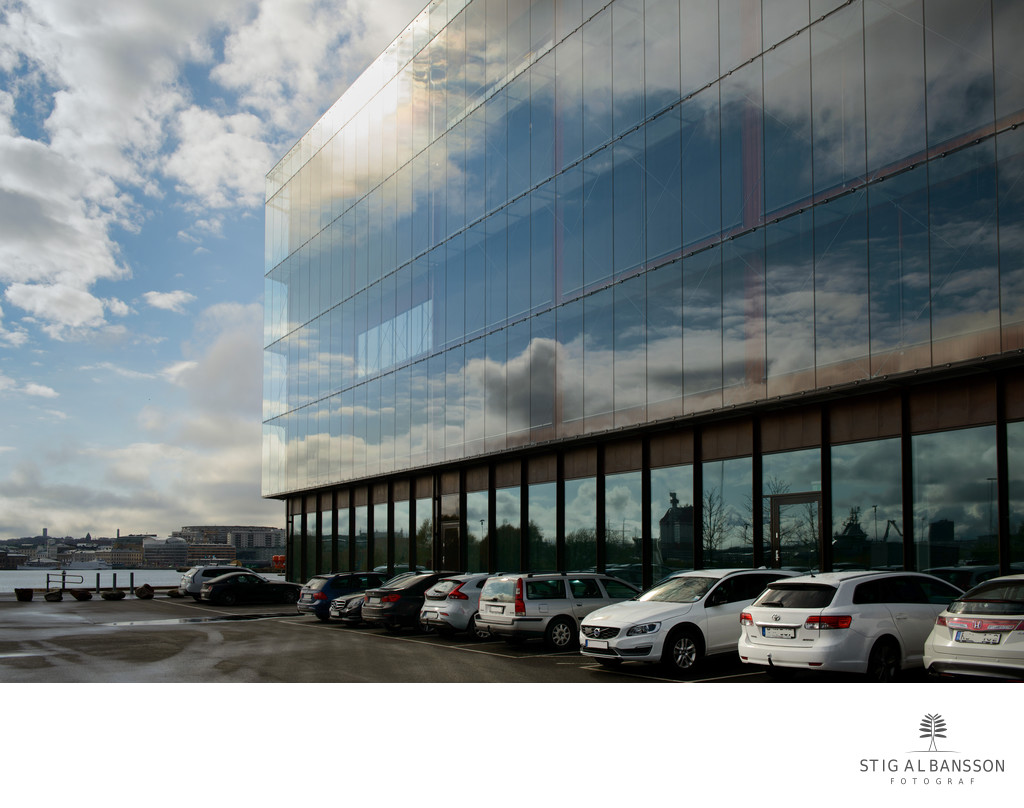 Spegling på Semcon´s fasad med bilar och molnhimmel