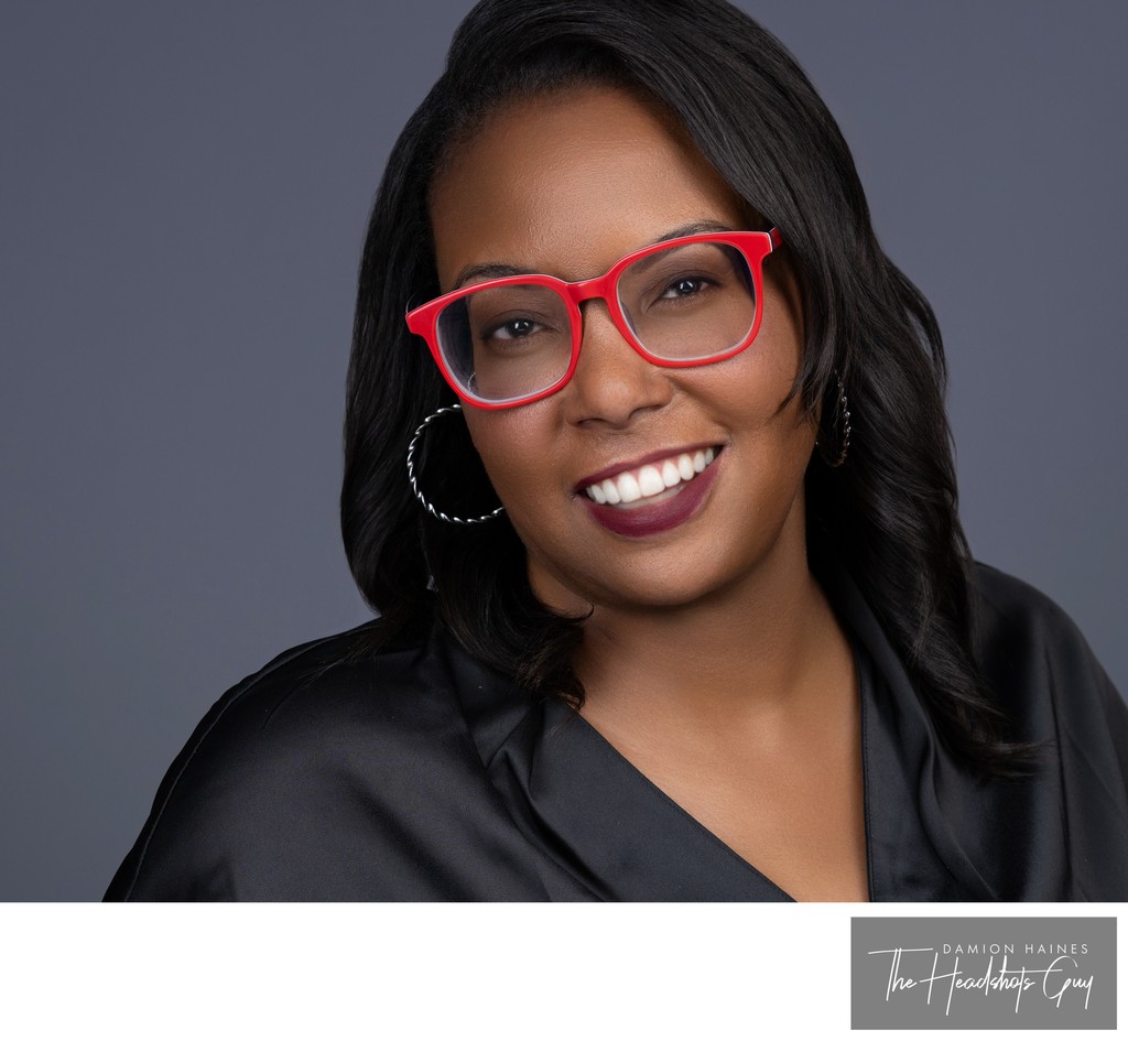 Business headshot of woman with distinctive red glasses