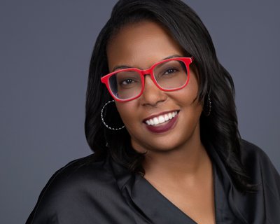 Business headshot of woman with distinctive red glasses