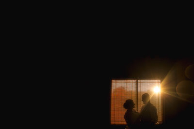 Silhouette of bride and groom against window