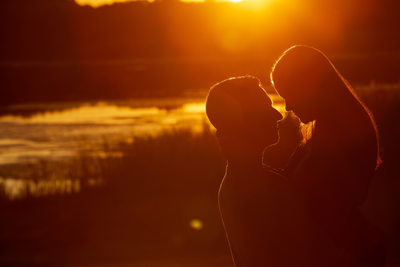 Engaged couple silhouette by pond