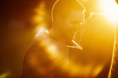 engaged couple smiling with sun flare