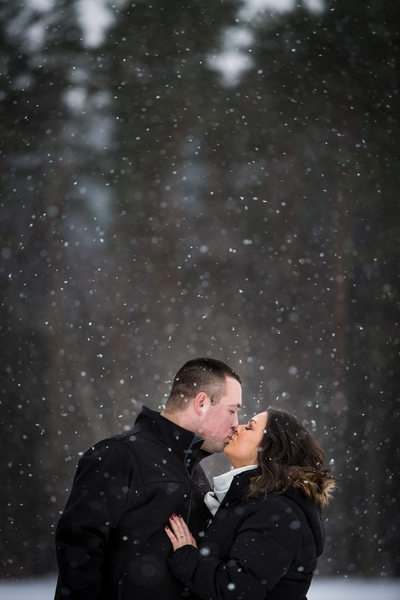 Engaged couple kissing in the snow
