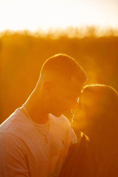 Engaged couple touching foreheads at sunset