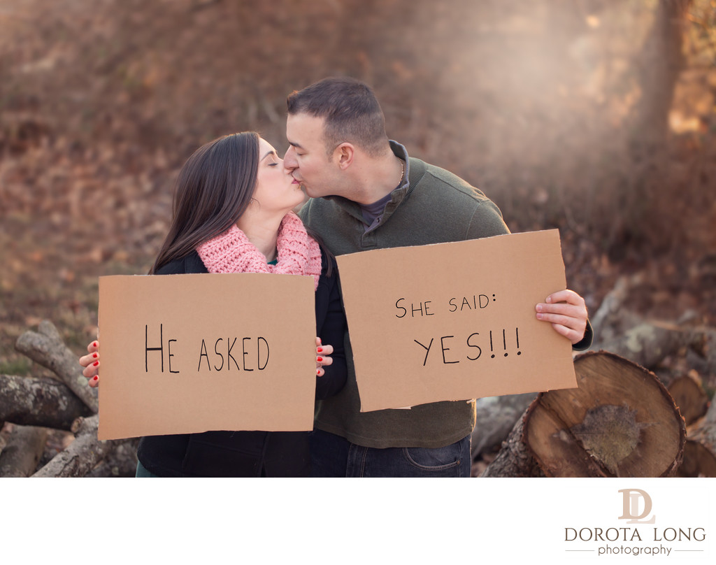 engaged couple kissing and holding cardboard signs