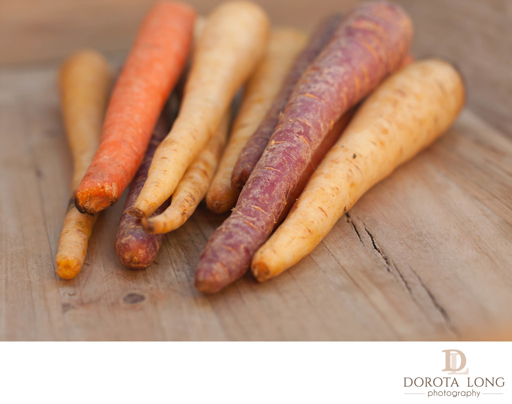 different colored fresh picked assorted carrots and parsnips on wooden background