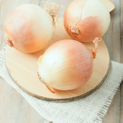 three whole onions on chopping board