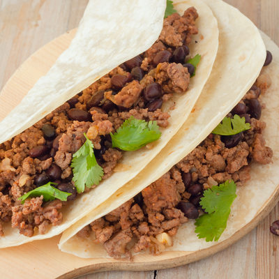 Two meat tacos with black beans garnished with cilantro
