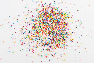 Colorful round sprinkles spilled on white background, isolated