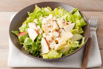 salad with apples and walnuts on rustic wooden background