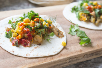 fresh tacos with chicken, vegetables and herbs on a wooden board