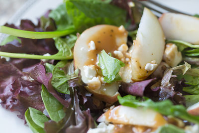 close up of a salad with apples, crumbled cheese and dressing