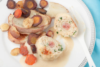a plate with meatballs made with ground white meat, ham, cheese and parsley served with roasted vegetables and white wine sauce