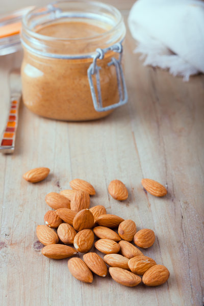raw organic almonds with almond butter at the background